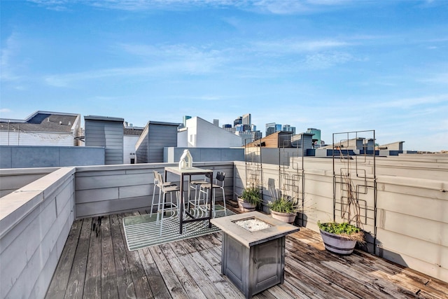 wooden terrace with an outdoor fire pit and a city view