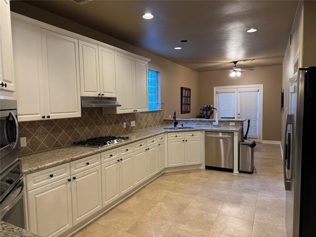 kitchen featuring under cabinet range hood, stainless steel appliances, a peninsula, a sink, and tasteful backsplash