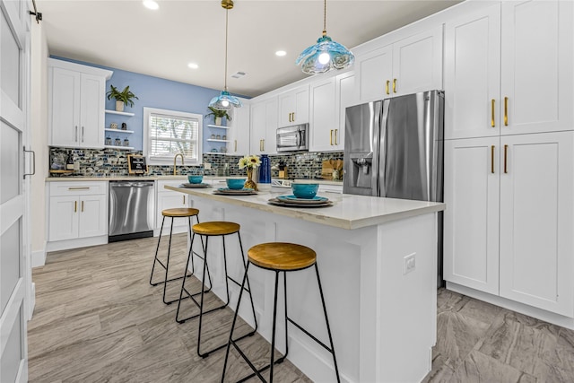 kitchen with stainless steel appliances, white cabinetry, backsplash, open shelves, and a kitchen bar