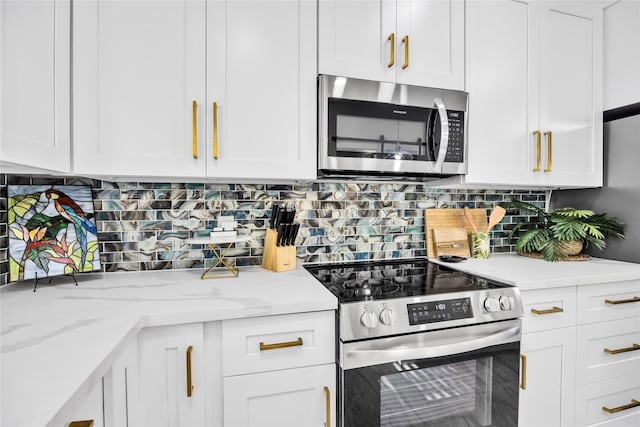 kitchen featuring stainless steel appliances, light stone countertops, white cabinetry, and tasteful backsplash