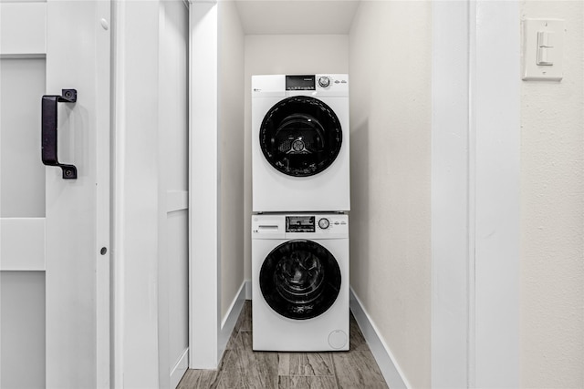 laundry area with laundry area, baseboards, light wood finished floors, and stacked washer / drying machine