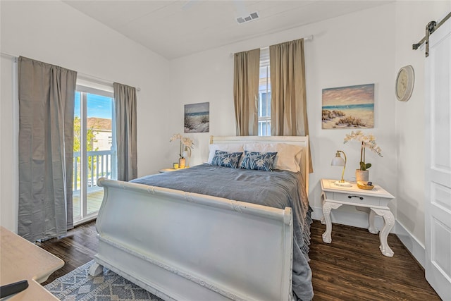 bedroom with a barn door, wood finished floors, visible vents, baseboards, and access to exterior