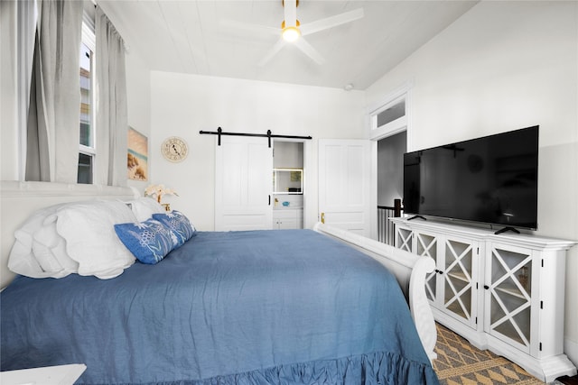 bedroom with ceiling fan and a barn door