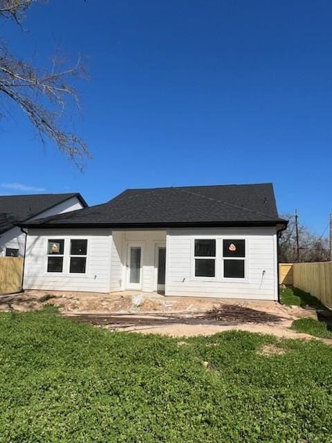 rear view of house with fence and a lawn