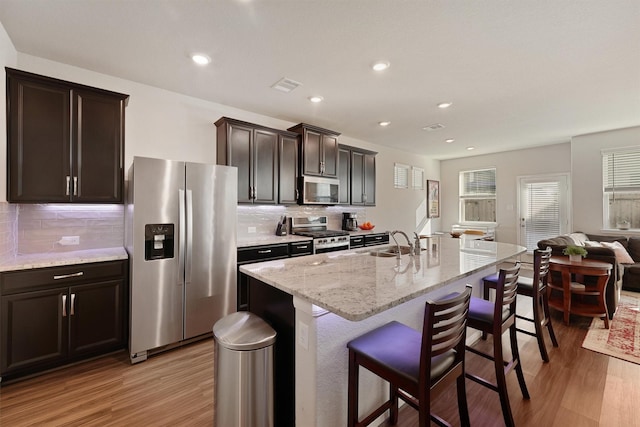 kitchen with stainless steel appliances, a breakfast bar, a sink, and light wood finished floors