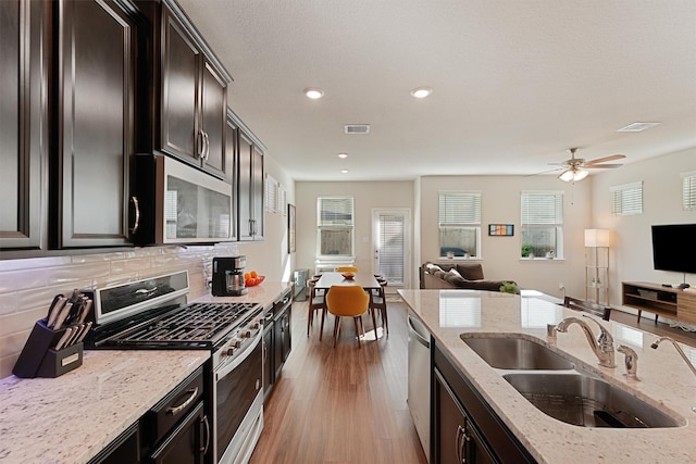 kitchen featuring visible vents, open floor plan, a sink, stainless steel appliances, and backsplash