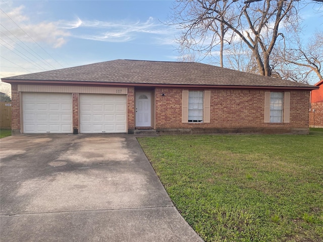 ranch-style home featuring a garage, concrete driveway, a shingled roof, and a front lawn