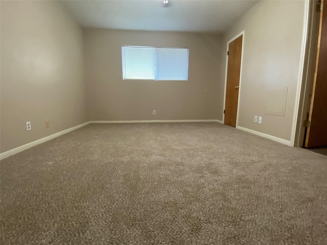 carpeted spare room featuring baseboards