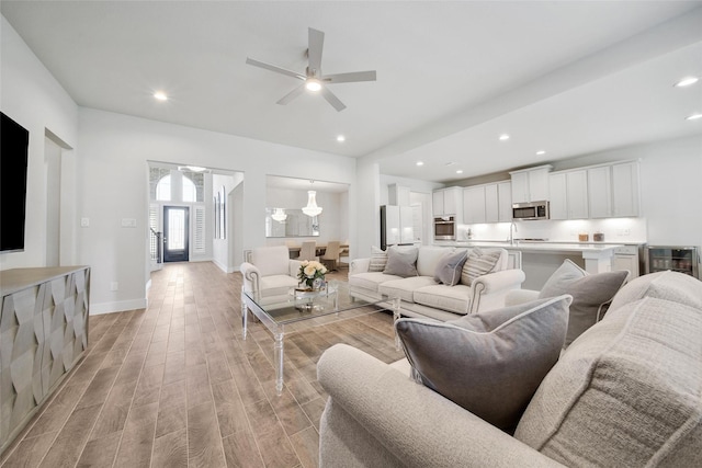 living room with beverage cooler, light wood finished floors, recessed lighting, and baseboards