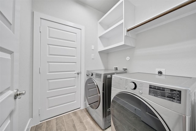 washroom featuring washing machine and dryer, laundry area, and wood finish floors