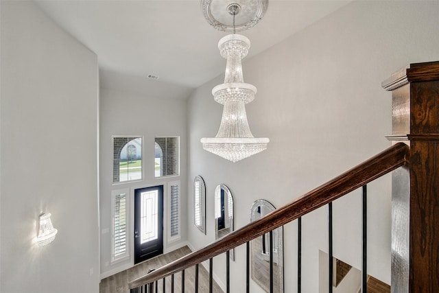 entrance foyer with a notable chandelier, visible vents, wood finished floors, baseboards, and stairs