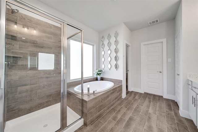 full bath featuring a stall shower, wood finished floors, visible vents, and a bath