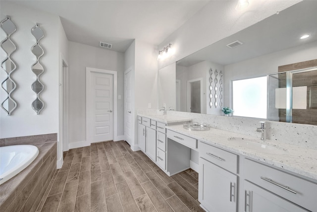 bathroom with wood finish floors, a sink, visible vents, and a stall shower