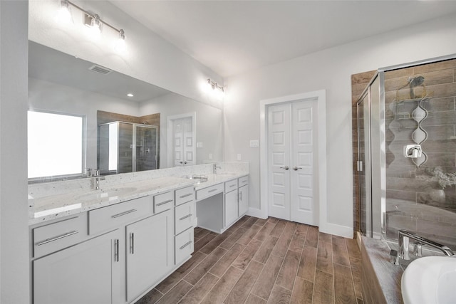 full bath featuring vanity, baseboards, visible vents, a shower stall, and wood tiled floor