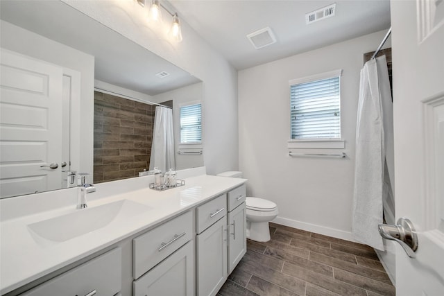 full bathroom with visible vents, toilet, wood tiled floor, a sink, and baseboards