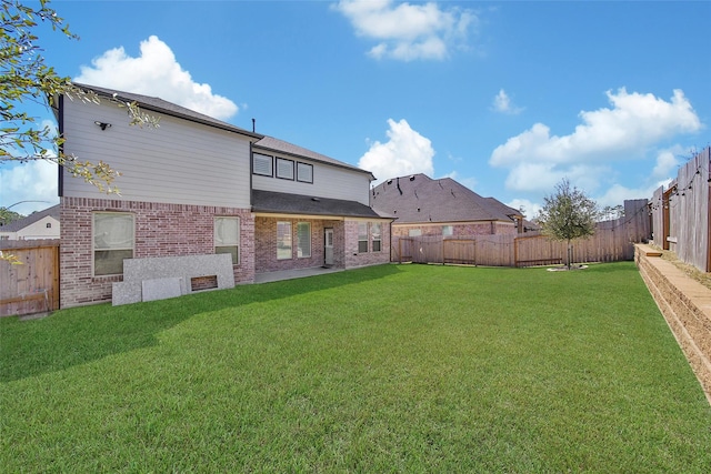 rear view of property with a yard, a fenced backyard, and brick siding