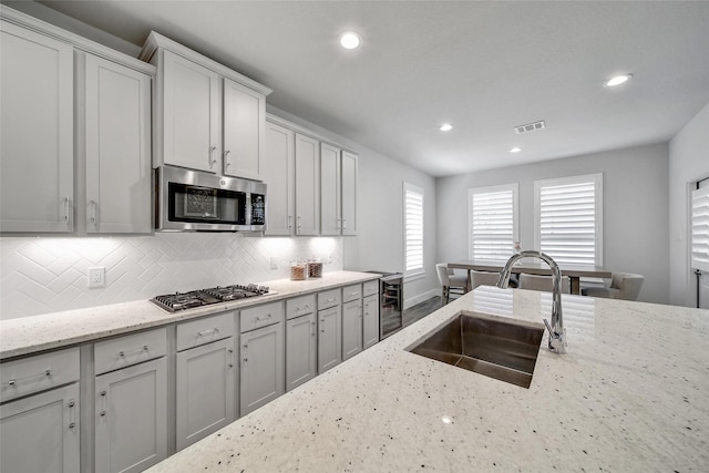 kitchen with beverage cooler, stainless steel appliances, a sink, visible vents, and tasteful backsplash