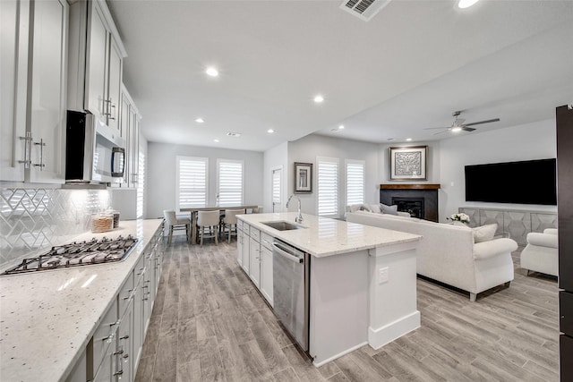 kitchen with visible vents, backsplash, appliances with stainless steel finishes, a sink, and light wood-type flooring