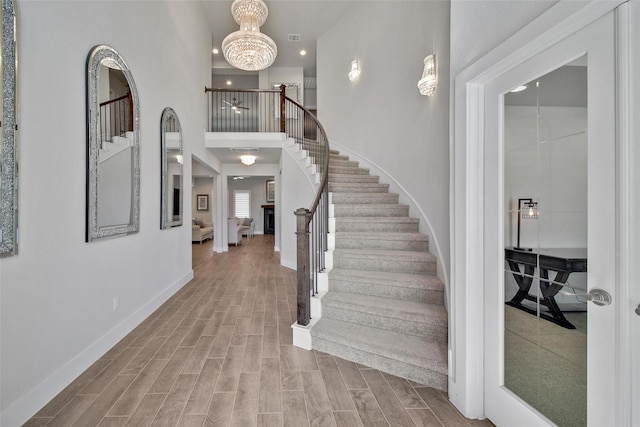 entrance foyer with baseboards, stairs, a chandelier, and wood finish floors