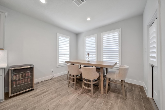 dining area featuring beverage cooler, visible vents, baseboards, light wood-style floors, and recessed lighting