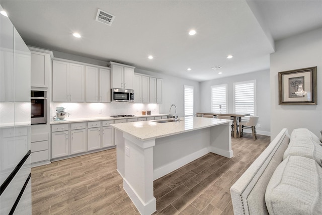 kitchen featuring stainless steel appliances, visible vents, backsplash, light wood-style floors, and a sink