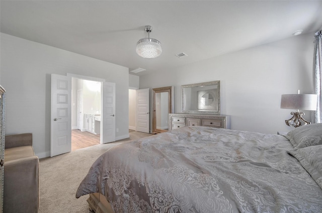 bedroom with light carpet, baseboards, visible vents, and ensuite bathroom