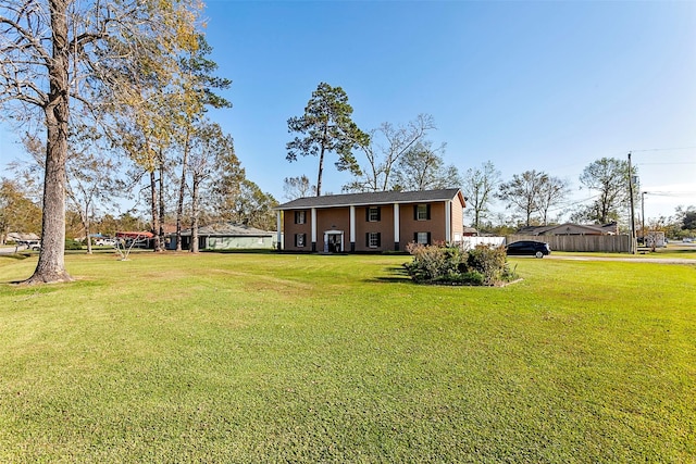 raised ranch featuring a front lawn and fence