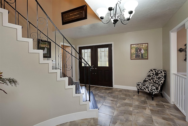 entryway with a textured ceiling, stairway, a chandelier, and baseboards