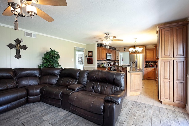 living room featuring visible vents, ornamental molding, ceiling fan, a textured ceiling, and light wood-type flooring