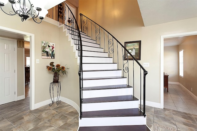 stairway featuring baseboards and a chandelier