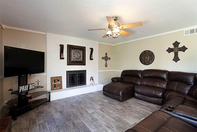 living area featuring ornamental molding, a fireplace, dark wood finished floors, and a textured ceiling