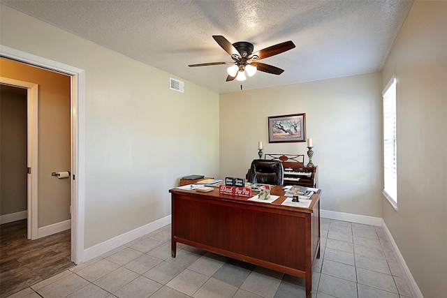 office space with light tile patterned floors, visible vents, a ceiling fan, a textured ceiling, and baseboards