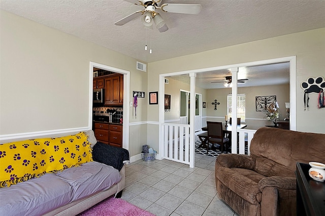 living area featuring visible vents, ceiling fan, a textured ceiling, and light tile patterned floors