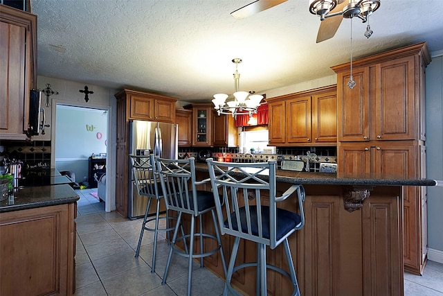 kitchen featuring tasteful backsplash, light tile patterned flooring, and brown cabinets