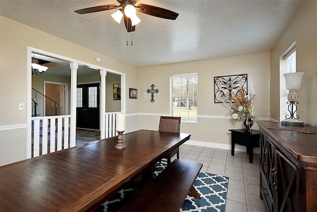 dining room featuring light tile patterned floors, decorative columns, baseboards, ceiling fan, and a textured ceiling