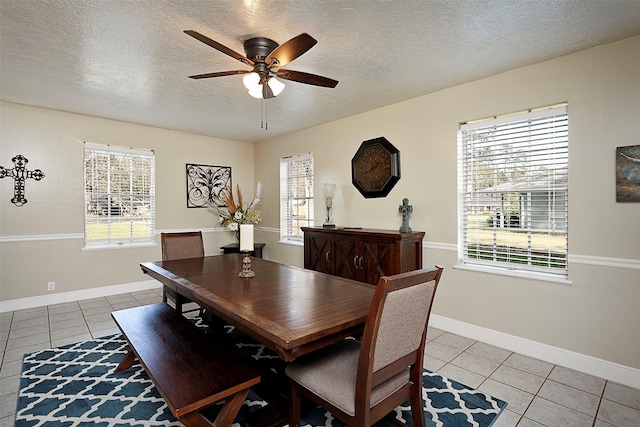 dining room with light tile patterned floors, a textured ceiling, a ceiling fan, and baseboards