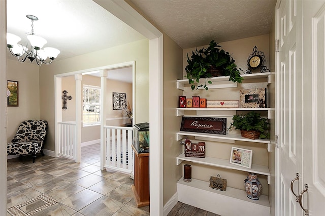 corridor with a textured ceiling, baseboards, and an inviting chandelier