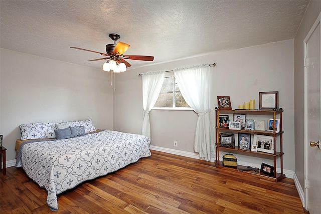 bedroom featuring a ceiling fan, a textured ceiling, baseboards, and hardwood / wood-style flooring