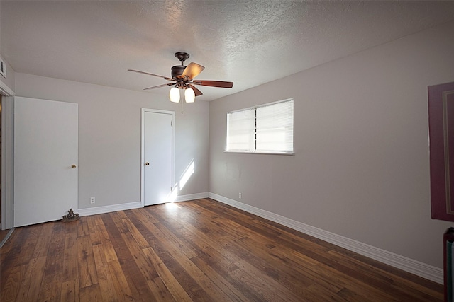 spare room with dark wood-style floors, a ceiling fan, baseboards, and a textured ceiling