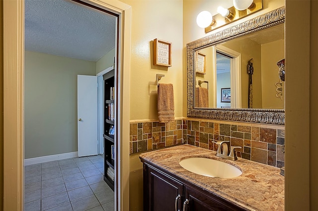 bathroom with a textured ceiling, baseboards, vanity, and tile patterned floors