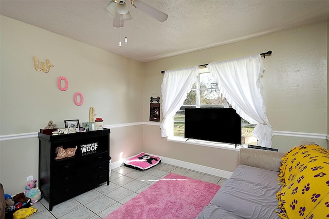 tiled living area featuring baseboards, a ceiling fan, and a textured ceiling