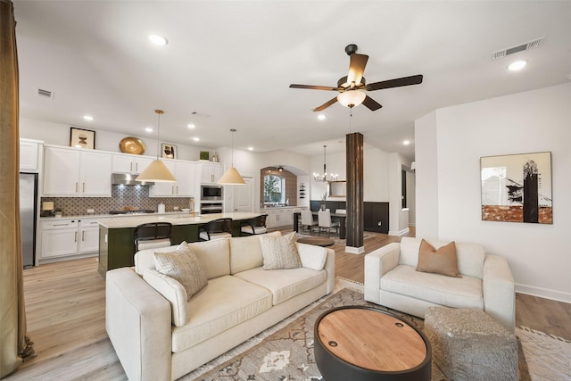 living area featuring recessed lighting, visible vents, light wood-style floors, baseboards, and ceiling fan with notable chandelier