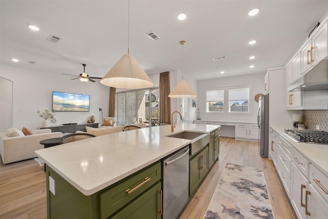 kitchen with an island with sink, visible vents, appliances with stainless steel finishes, and green cabinets