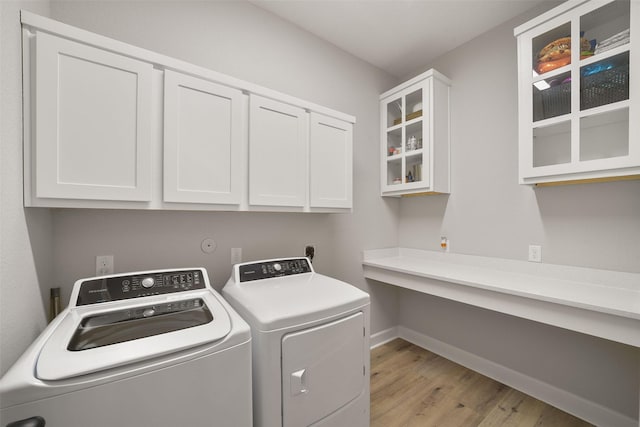 laundry area featuring cabinet space, washing machine and dryer, baseboards, and light wood finished floors