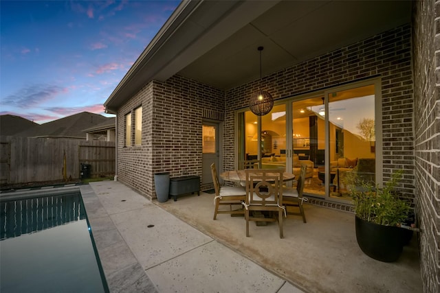 patio terrace at dusk featuring fence and a fenced in pool