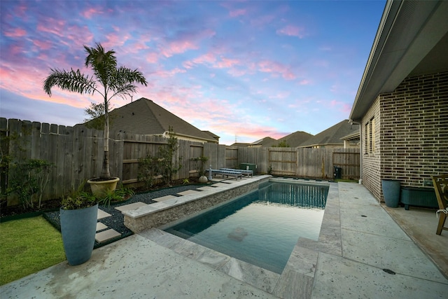 pool at dusk featuring a patio and a fenced backyard