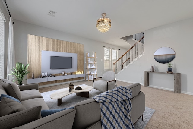 carpeted living room with an inviting chandelier, visible vents, stairway, and baseboards