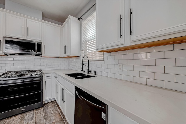 kitchen with decorative backsplash, appliances with stainless steel finishes, light countertops, white cabinetry, and a sink