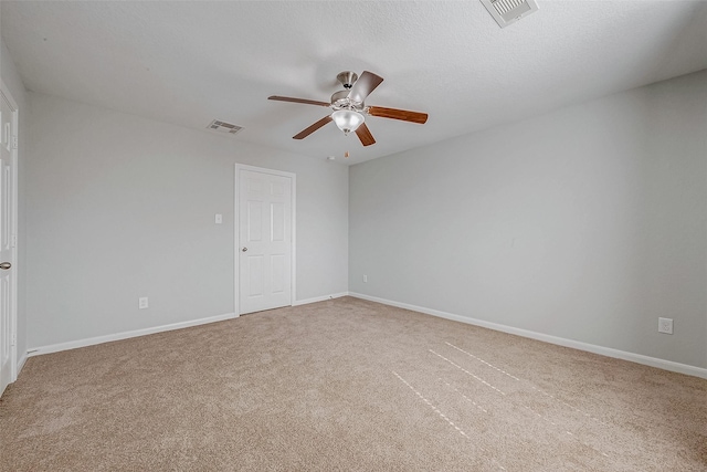 carpeted empty room with baseboards, visible vents, and a ceiling fan