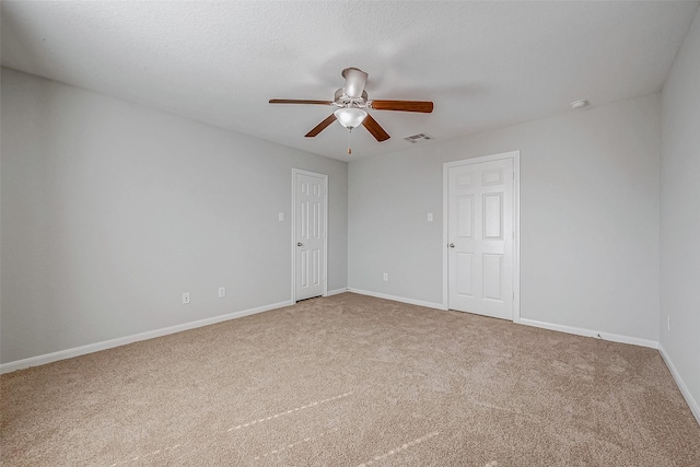 unfurnished room featuring carpet floors, visible vents, ceiling fan, a textured ceiling, and baseboards